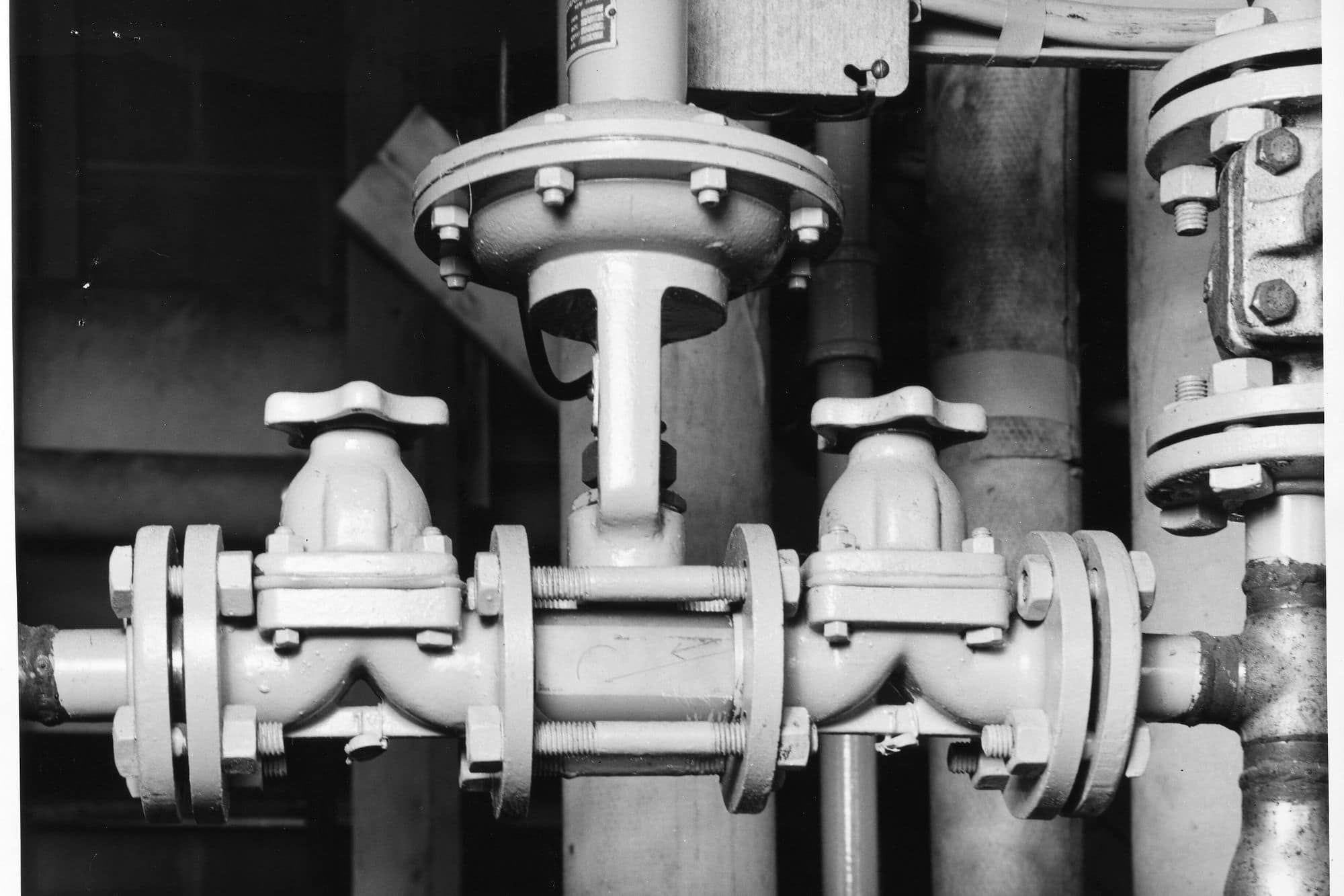 Black-and-white detail of flanged valves and process pipework